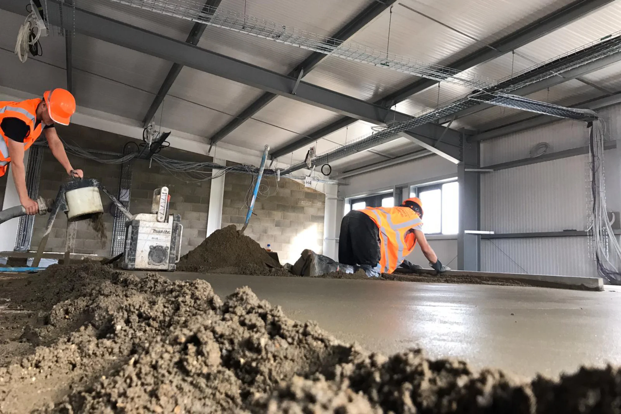 Vakmannen leggen een chape in een industriële hal