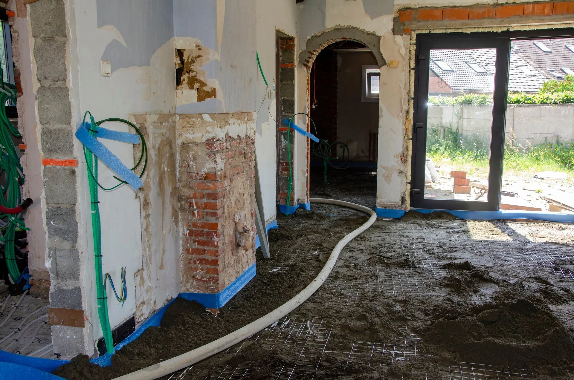 Renovatie: de chape wordt met een slang binnengepompt over het wapeningsnet, met blauwe randstroken langs de muren